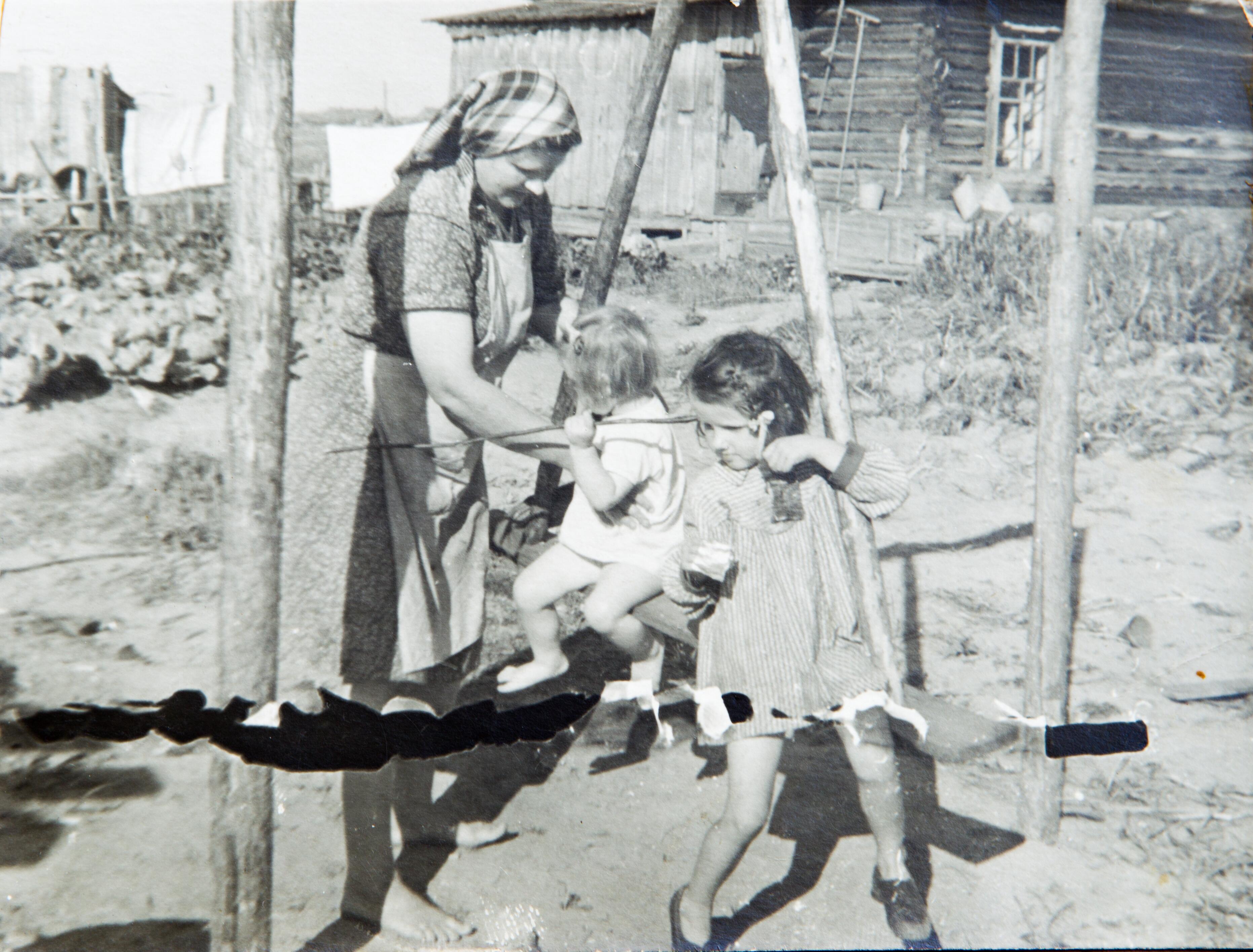 1953-ieji: pirmoji tremties vieta Krasnojarsko krašte – Revučis, kur prieš tai veikė garsusis 7-asis lageris. Marija Skučienė su dukrelėmis Birute ir Virginija (dešinėje) prie P. Skučo įrengtų sūpynių.