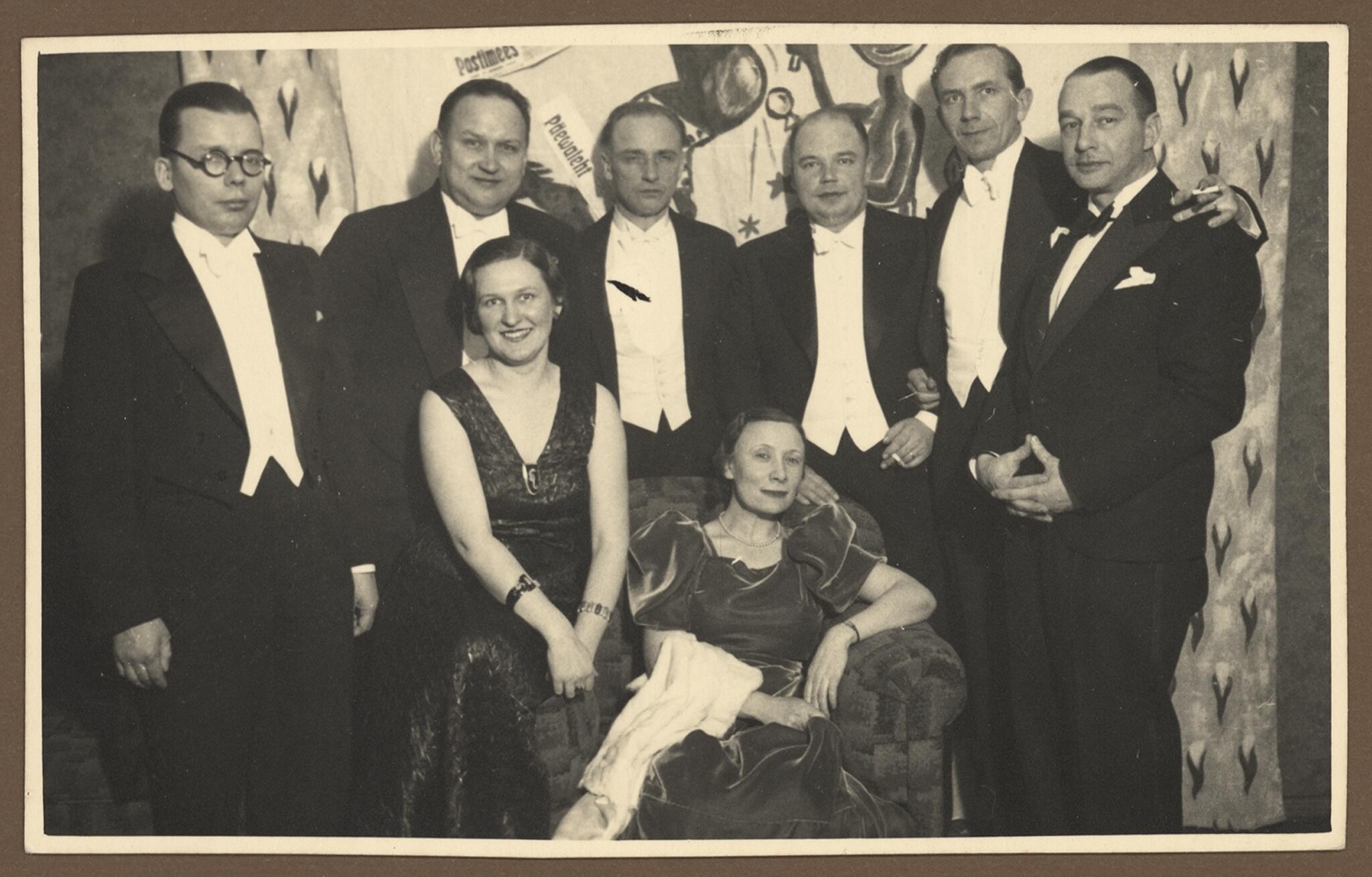 Iškilmės: spaudos balius Taline. Stovi (iš kairės) trečias – M. K. Čiurlionio galerijos direktorius Paulius Galaunė, fotelyje sėdi Lietuvos URM Spaudos biuro viršininkė M. Avietėnaitė. XX a. 4-asis dešimtmetis.
