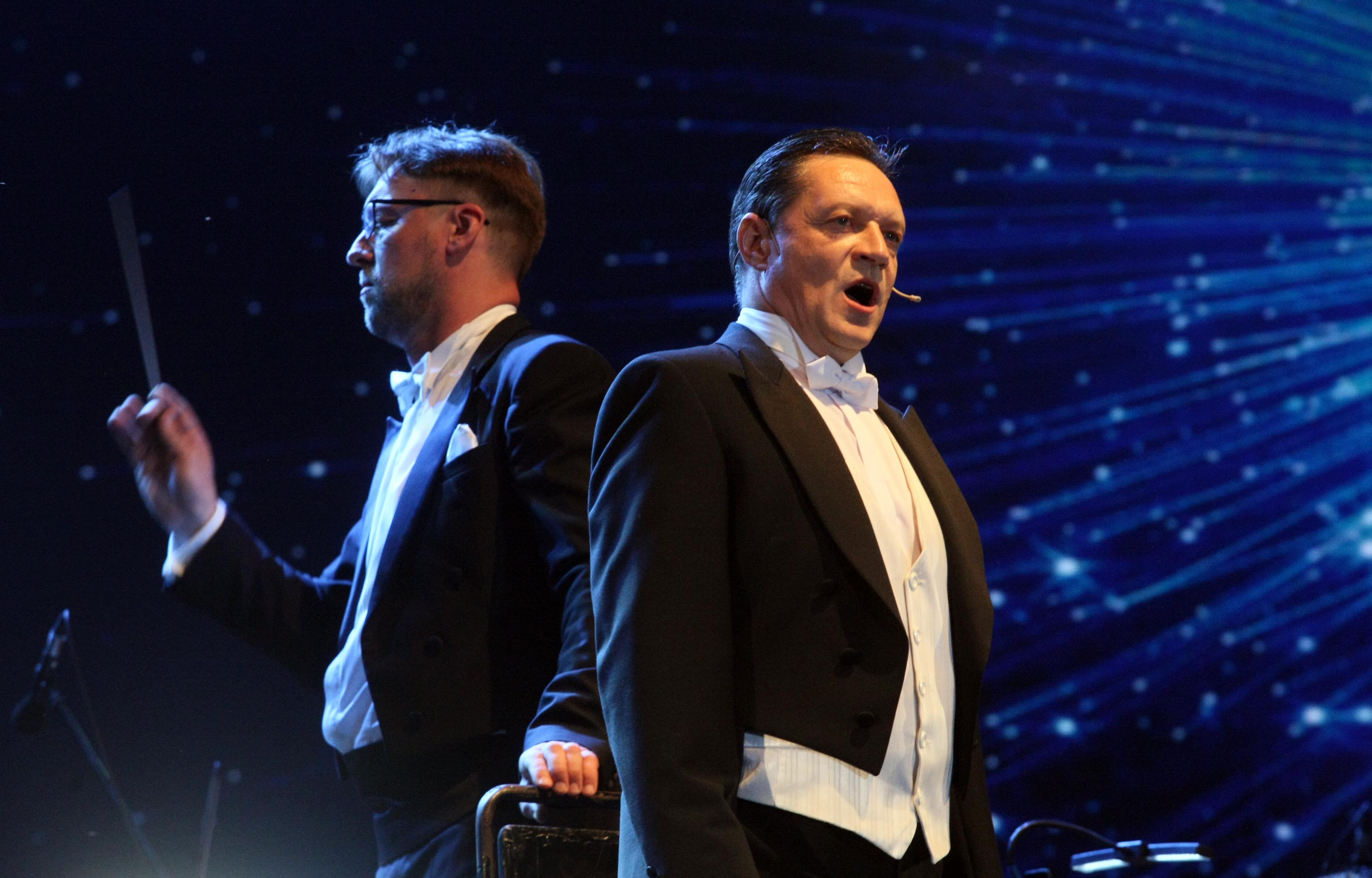 Tiltas: dirigentas metaforiškai apibūdinamas kaip nematomas, bet jo įtaka muzikiniam skambesiui yra akivaizdi. Jis sukuria bendrą muzikos interpretaciją ir subtiliai valdo šventės atmosferą. 