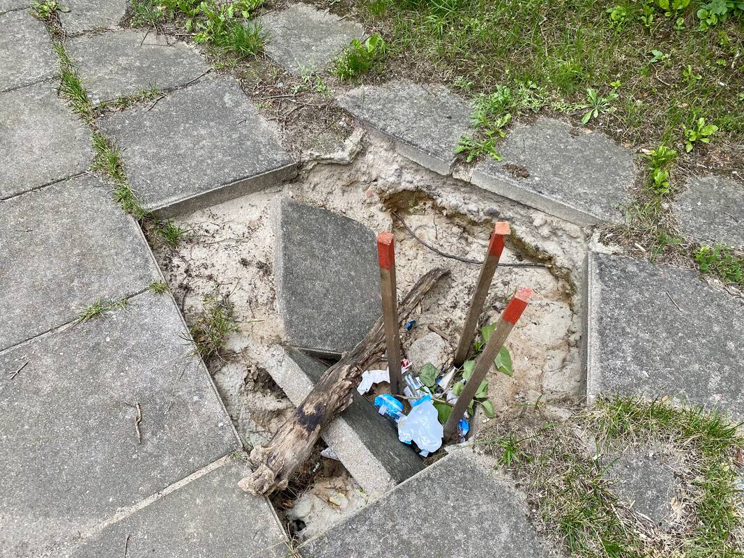 Problema: atsivėrusi įgriuva pamažu virsta šiukšliadėže – praeiviai į ją jau meta įvairias atliekas.