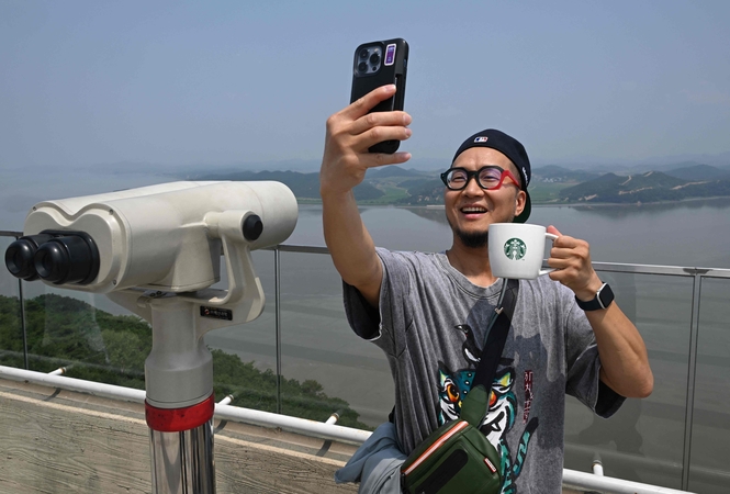 Turistai plūsta į „Starbucks“ kavinę su vaizdu į Šiaurės Korėją