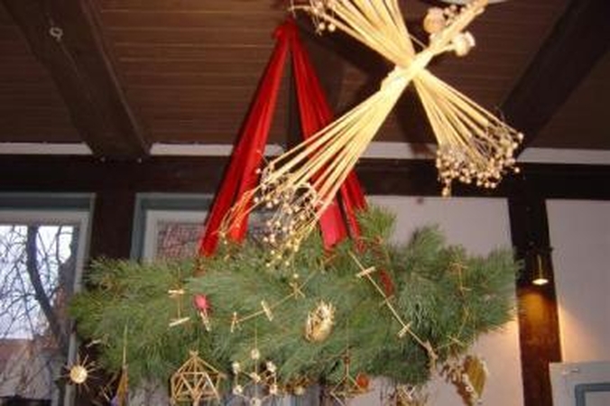 Dermė: spygliuočių tamsyje šiaudinės puošmenos atsispindi auksu.